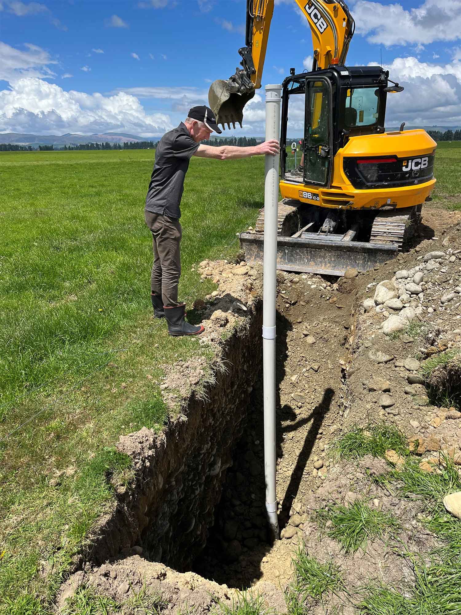 A dairy farmer with a JCB constructing a water well in a paddock
