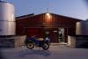 A blue farm motorbike parked outside a farm dairy in the early morning