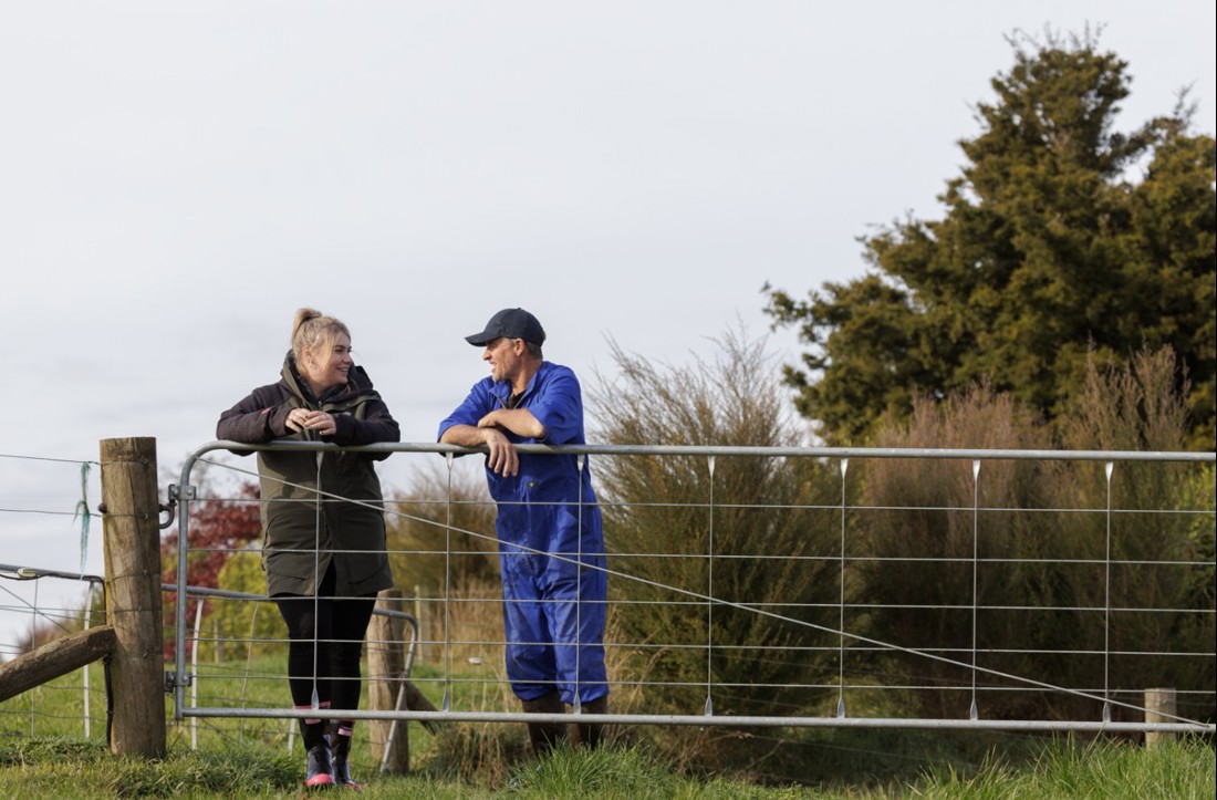 A farm consultant and a dairy farmer leaning on a gate discussing farm effluent