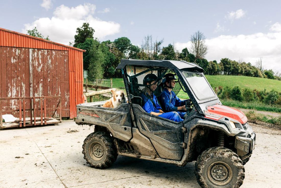 Dairy farm workers in a muddy all terrain vehicle in the farm yard