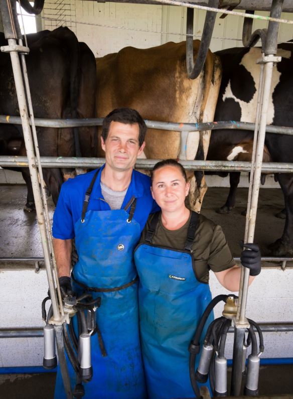 Dairy farmers Danielle and Bevan Cornelius in the milking shed with cows in the background